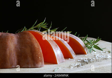 Closeup of slices of pumpkin with rosemary on wooden table. Raw vegetables. Stock Photo