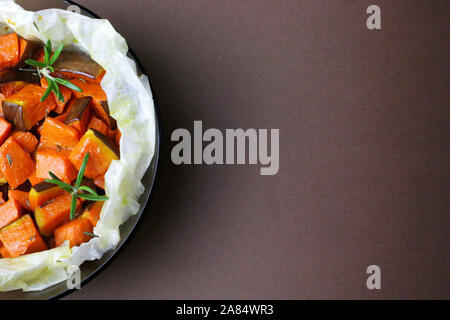 Top view of baked pumpkin with rosemary on dark background. Stock Photo