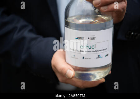 Eggenstein Leopoldshafen, Germany. 06th Nov, 2019. A visitor to a ceremony celebrating the commissioning of a research plant that can generate CO2-neutral fuel from air and green electricity using 'Power-to-X' technologies (P2X) has a bottle of e-fuel in his hand on the North Campus of the Karlsruhe Institute of Technology (KIT). Credit: Marijan Murat/dpa/Alamy Live News Stock Photo