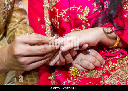 Bride places the wedding ring on the Groom’s finger at Bangladesh. Close up image. Stock Photo