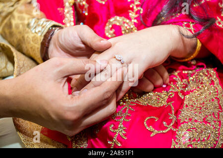 Bride places the wedding ring on the Groom’s finger at Bangladesh. Close up image. Stock Photo