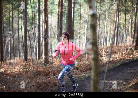 Woman running on trail in autumn woods Stock Photo