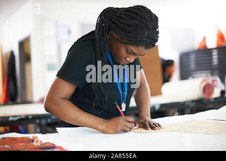 Focused female fashion designer tracing sewing patter in studio Stock Photo