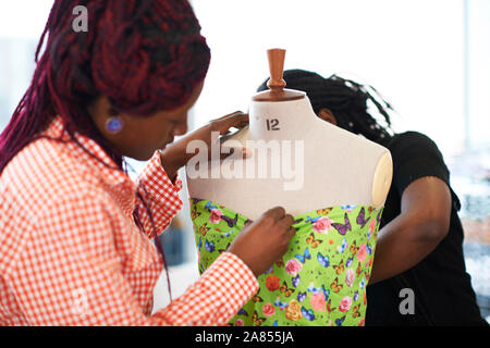 Female fashion designers pinning butterfly fabric on dressmakers model