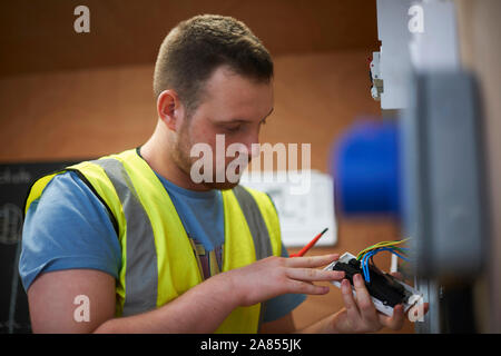 Male electrician student examining light switch in workshop Stock Photo