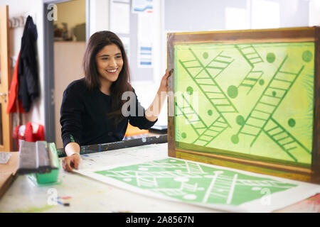 Smiling female art student screen printing in art studio Stock Photo