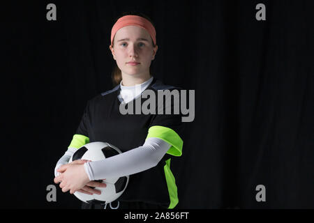 Portrait confident teenage girl soccer player holding soccer ball Stock Photo