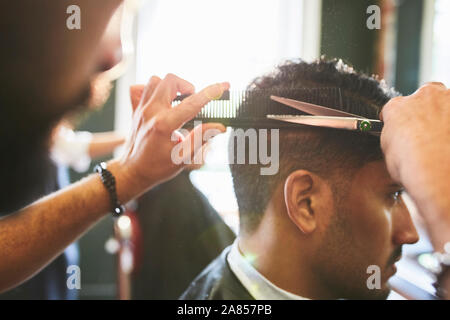 Male barber giving customer a haircut in barbershop Stock Photo