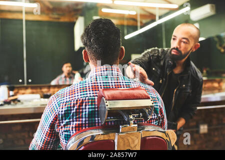 Male barber checking haircut of customer in barbershop Stock Photo