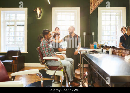 Male barbers and customers in barbershop Stock Photo