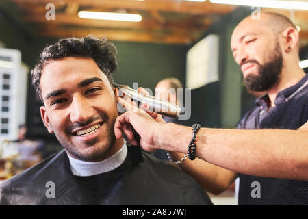 Portrait smiling young man receiving haircut at barbershop Stock Photo