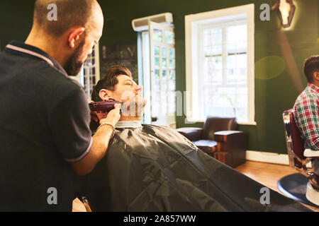 Man receiving a shave in barbershop Stock Photo