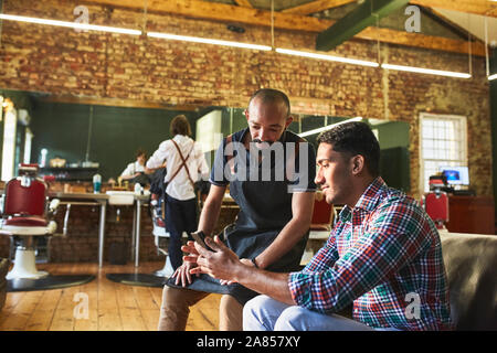 Male barber and customer with digital tablet in barbershop Stock Photo