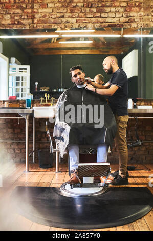 Male barber shaving face of customer in barbershop Stock Photo