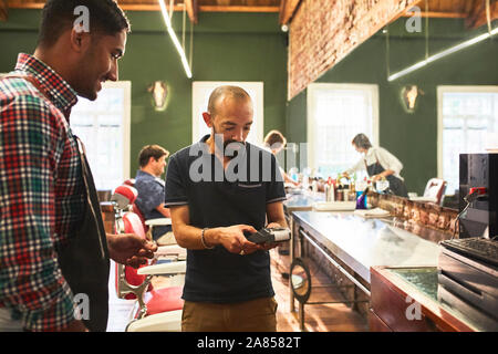 Male customer paying barber in barbershop Stock Photo