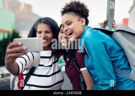 Happy mother and daughters backpacking, taking selfie with camera phone Stock Photo