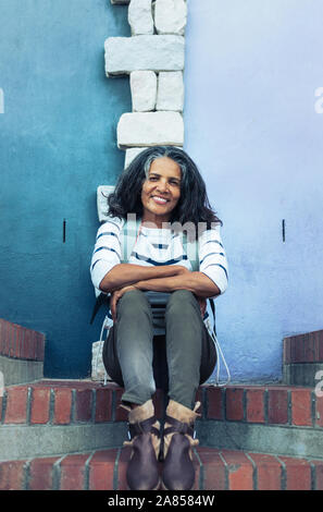 Portrait smiling, confident woman sitting on brick steps Stock Photo