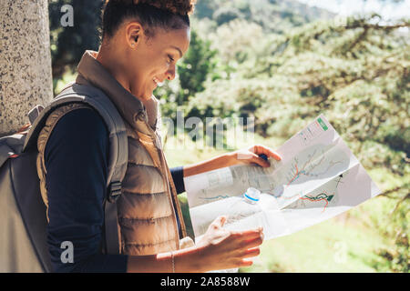 Young female hiker looking at trail map ins sunny woods Stock Photo