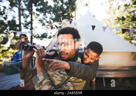 Curious father and son with binoculars at campsite Stock Photo