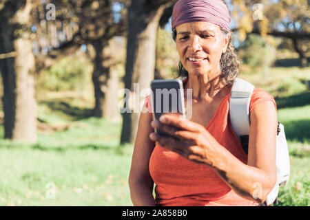 Female hiker using smart phone in sunny woods Stock Photo