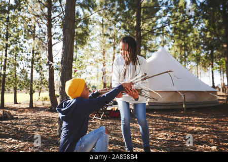 Mother and son gathering firewood kindling at campsite in woods Stock Photo