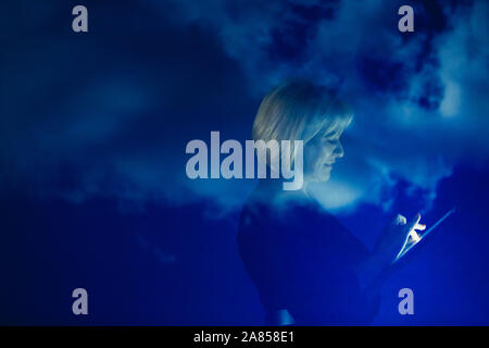 Double exposure businesswoman with digital tablet against blue sky with clouds Stock Photo