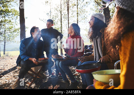 Family and friends eating at sunny campsite in woods Stock Photo