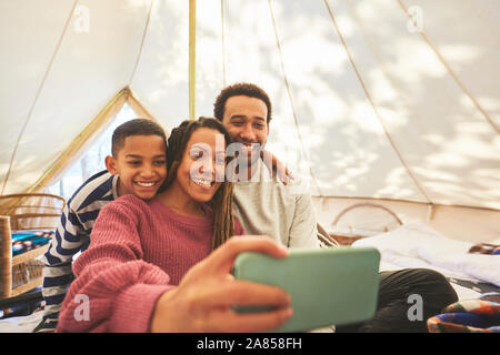 Happy, affectionate family taking selfie in camping yurt Stock Photo