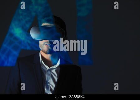 Double exposure businessman with virtual reality simulator glasses against AI text Stock Photo