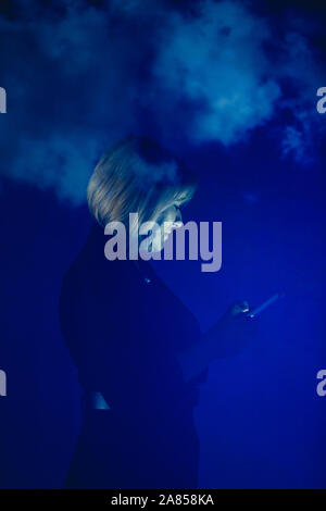Double exposure businesswoman using smart phone against blue sky with clouds Stock Photo