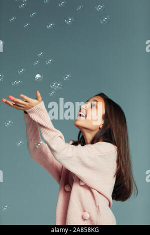 Playful, carefree girl catching falling bubbles Stock Photo