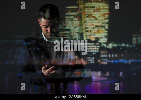 Double exposure businessman using smart phone against cityscape at night Stock Photo