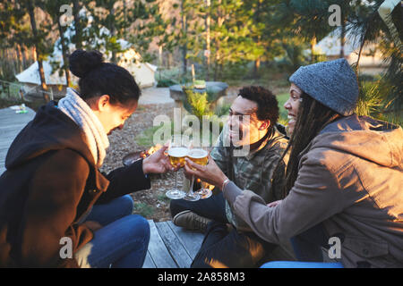 Happy friends toasting wine glasses at campsite in woods Stock Photo