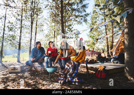 Family cooking at campsite grill in sunny woods Stock Photo