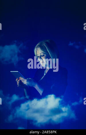 Double exposure businesswoman using digital tablet against blue sky with clouds Stock Photo