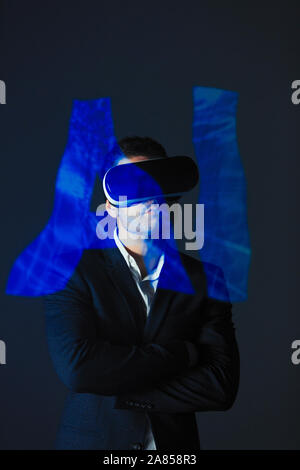 Double exposure businessman with virtual reality simulator glasses and AI text Stock Photo