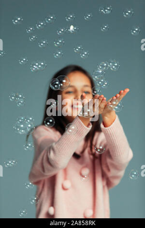 Happy, playful girl catching falling bubbles Stock Photo
