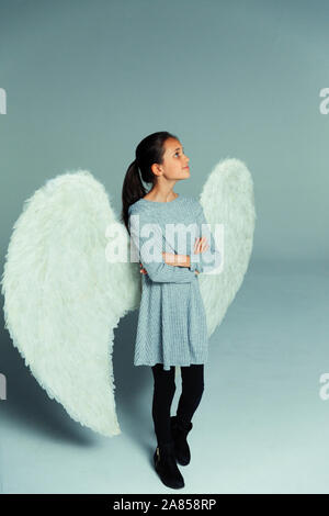 Portrait confident, curious girl wearing angel wings, looking up Stock Photo