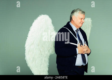 Smiling businessman wearing angel wings Stock Photo