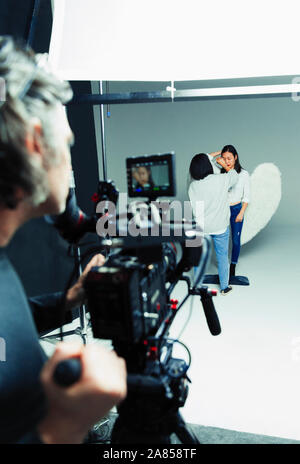 Photographer waiting for makeup artist and model in angel wings during studio photo shoot Stock Photo