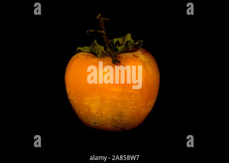 Beautiful orange ripe persimmon against a black background in halloween style Stock Photo
