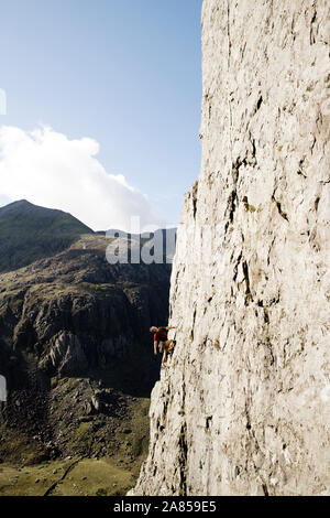 Male rock climber scaling large rock face Stock Photo