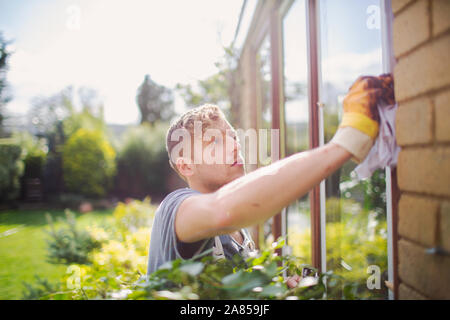 Male painter painting home exterior window trim Stock Photo