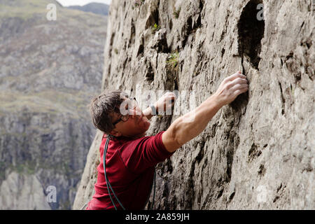 Focused male rock climber scaling rock face Stock Photo