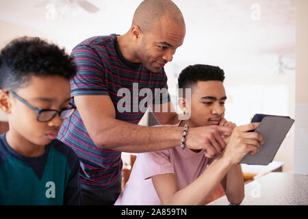 Father and teenage son using digital tablet Stock Photo