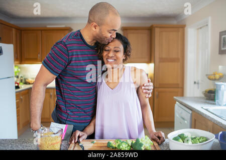 Affectionate husband hugging wife cooking in kitchen Stock Photo