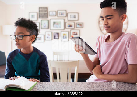 Brothers reading and using digital tablet in kitchen Stock Photo