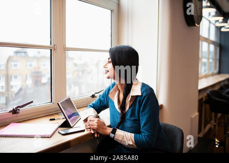 Thoughtful businesswoman working at digital tablet in office window Stock Photo