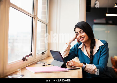 Portrait confident, smiling businesswoman using digital tablet in window Stock Photo
