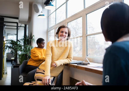 Smiling businesswomen talking in office Stock Photo